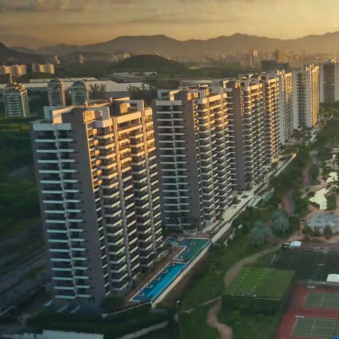 Fachada de um dos edifícios do Astra Ilha Pura Smart Facilities ao entardecer, com as montanhas da Barra ao fundo