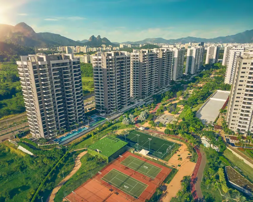 Vista aérea dos edifícios do Astra Ilha Pura Smart Facilities entre o Parque Ilha Pura, as quadras de tênis e as montanhas
